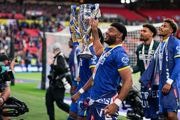 AFC Wimbledon takımından Ryan Johnson, 26 Mayıs 2025 'te Wembley Stadyumu' nda oynanan Wimbledon-Walsall maçından sonra taraftarlarıyla birlikte reklamı kutluyor.