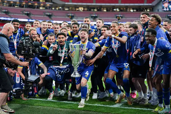 Wimbledon oyuncuları, 26 Mayıs 2025 'te Wembley Stadyumu' nda oynanan Wimbledon-Walsall maçında Sky Bet 2 Playoff Finali 'nin taraftarları önünde kupayı kaldırır.