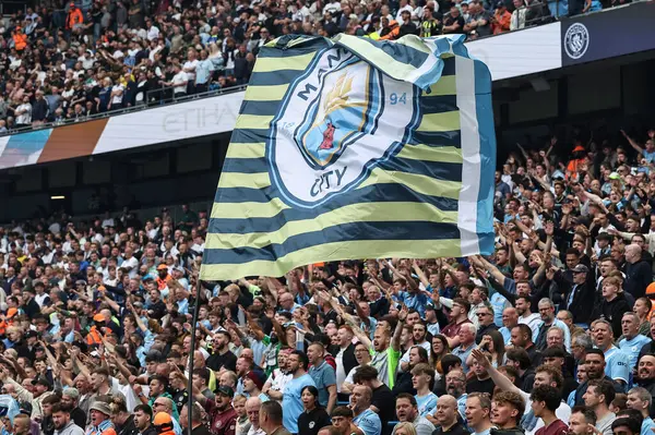 Manchester City taraftarları, 23 Ağustos 2025 tarihinde Etihad Stadyumu 'nda Manchester City ile Tottenham Hotspur arasında oynanan Premier League karşılaşmasında bayrak sallıyor.