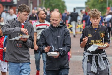 Manchester United taraftarları Premier Lig maçında Old Trafford 'a giderken Manchester United' a karşı Old Trafford, Manchester, İngiltere 'de 30 Ağustos 2025' te bir şeyler atıştırıyorlar.