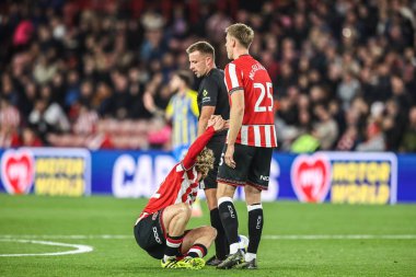 Sheffield United 'dan hakem Adam Herczeg ve Mark McGuinness, 30 Eylül 2025' te Bramall Lane, İngiltere 'de oynanan ve Sheffield United' ın Southampton 'a karşı oynadığı maçta sakatlandığı maçta Sheffield United' tan Tom Davies 'i kontrol ediyorlar.