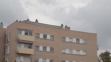 Bu, yağmurlu ve kasvetli bir günde bazı binaların yakınındaki bir parkta çekilmiş bir resim. Yağmur yağacak gibi görünüyor..