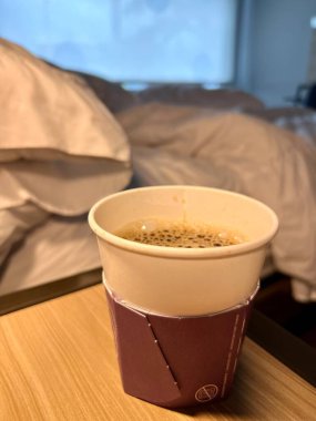 Boş bir motel odasının içi. Tek kullanımlık kağıt kahve üzerine odaklanmış.