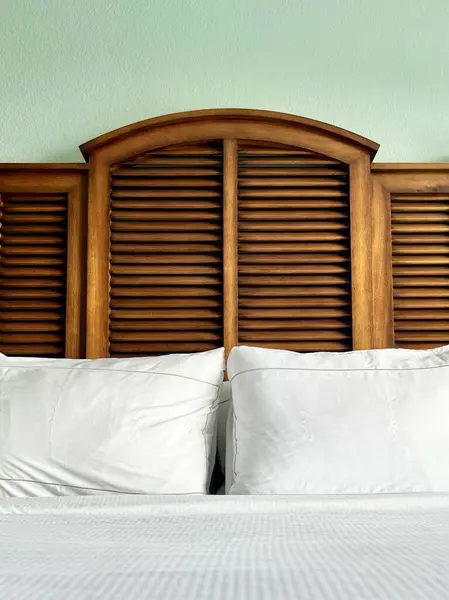 Design details in bedroom with crisp white bedding, sea foam green walls and natural wood headboard