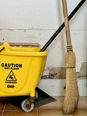 Sarı süpürge kovası, paspas ve süpürge eski püskü dolap bölgesinde. 