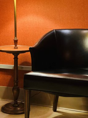 Deri sandalyeli turuncu iç duvar ve düşük ışıkta yer lambası.