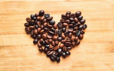 kalp simgesi, kavrulmuş kahve çekirdeği rustik ahşap arka planda