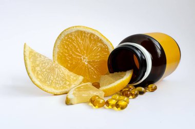 Vitaminli kavanoz, kapsüllerde C vitamini ve beyaz arka planda limonlar. Vitaminler, sağlıklı yaşam tarzı, beyaz arka planda izole edilmiş kapsül sarı haplar. İlaçlar, vitamin terapisi konsepti