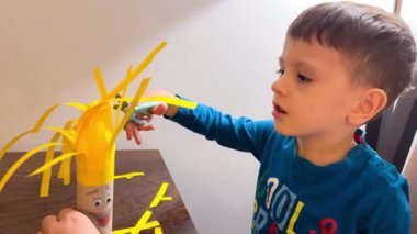 Bir çocuk renkli kağıdı kırtasiye makası ile keser. Makasla kes. Anaokulu yaşı ve gelişimi. Çocuk el işi yapıyor. El yapımı el sanatları... iyi motor becerilerin geliştirilmesi..