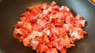 Modern bir mutfak sobasında, siyah, yapışmaz tavada pişmeye hazır çiğ et. Minimalist mutfak arka planı ve doğal ışıklandırma..