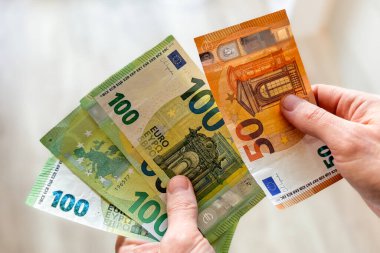 Avro banknotlarını sayan bir adamın elleri. Para sayan bir adamın ellerine yakın çekim. Finansal yönetim, enerji maliyetleri, kış mevsiminde tasarruf ve enflasyon.