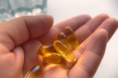 Omega yağ tabletleri elimizde. Akşam çuha çiçeği, omega-6 ve bir kadının elinde balık yağı takviyesi olan kapsüller. vitamin alıyordum.