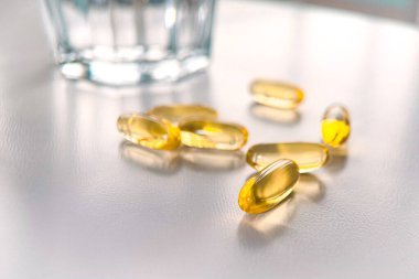 Altın balık yağı kapsülleri. Beyaz arka planda iyi bir sağlık için besin takviyeleri. Tamamlayıcı beslenme. Omega-3. Sağlık ve sağlıklı beslenme kavramı.