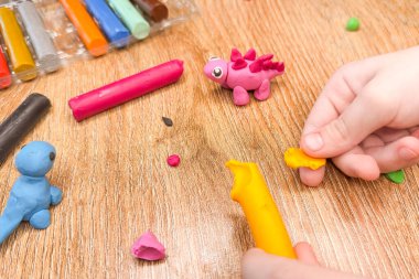 Evde plasticine 'den yaratıcı çocuk modelliği. Çocuk, ellerin motor becerilerini geliştirmek için plastikle oynuyor. Çocuk bir dinozor heykeli yapıyor. Yüksek kalite fotoğraf.