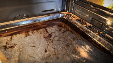 Mutfaktaki ağır yağlardan fırını temizliyorum. Ev eldivenini ve temizlik için sarı bir süngeri fırının arka planına odaklanmadan teslim et. Pişirme yüzeyleri için yağ önleyici.