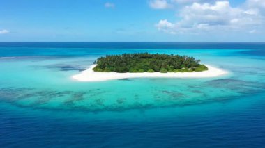 Turkuaz su ve beyaz kum plajı olan, güneşli bir adanın insansız hava aracı görüntüsü.