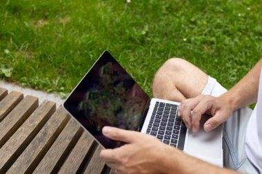 Yeni iş planı. Genç bir iş adamı dizüstü bilgisayarda çalışır. Çevrimiçi çalışırken, yeşil ekranlı açık bir bilgisayar defteri ile klavyeye yazar.