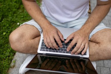 Yeni iş planı. Genç bir iş adamı dizüstü bilgisayarda çalışır. Çevrimiçi çalışırken, yeşil ekranlı açık bir bilgisayar defteri ile klavyeye yazar.