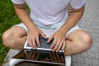 Yeni iş planı. Genç bir iş adamı dizüstü bilgisayarda çalışır. Çevrimiçi çalışırken, yeşil ekranlı açık bir bilgisayar defteri ile klavyeye yazar.