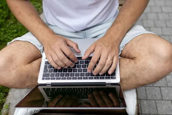 Yeni iş planı. Genç bir iş adamı dizüstü bilgisayarda çalışır. Çevrimiçi çalışırken, yeşil ekranlı açık bir bilgisayar defteri ile klavyeye yazar.