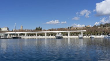 view of the alcazaba of Malaga from pier one, with yachts, and a blue sky.