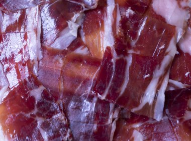 image of a white plate with serrano ham on a black background