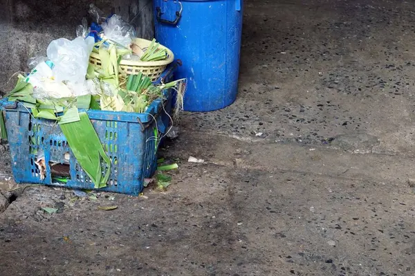 A trash bin and trash can on the ground in the bazaar market.
