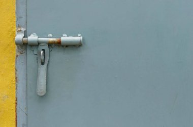 Gri boyanmış metal duvarlı arka planı olan metal bir kapı kolu..