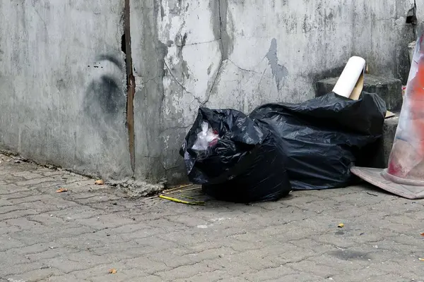 A black garbage on the street beside a cement box for collect garbage, enviroment concept.