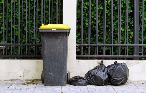 Uma Lixeira Sacos Lixo Preto Frente Uma Cerca Verde Conceito — Fotografia de Stock
