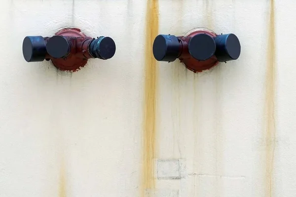 A both inlet valve of the fire water systems  on the old vintage cement wall with a rust stains.