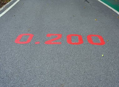 Parklardaki caddenin yüzeyinde 0.200 km işaretli kırmızı bir tabela