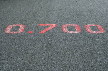 Parklardaki caddenin yüzeyinde 0,700 KM işaretli kırmızı bir tabela