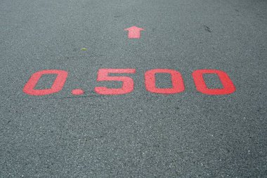 Parklardaki caddenin yüzeyinde 0.500 km işaretli kırmızı bir tabela.