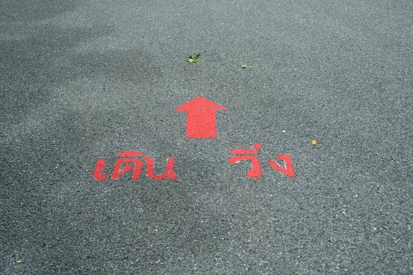 A red arrow sign straight marken on surface the street in the parks