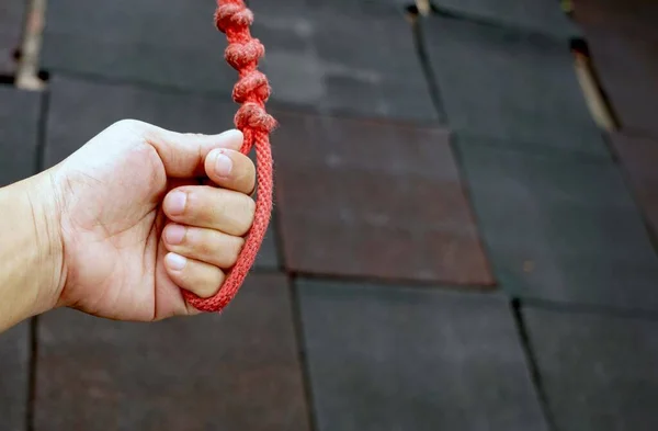 A old red rope in hand for exercise of a sport equipment for kids playing.
