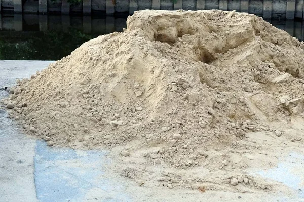 Close up a pile of sand in construction site beside a canal.