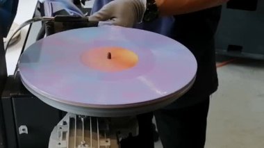 Bir işçi, mühürlü işlemden sonra fonograf disk kaydının kenar kesme işlemcisiydi.