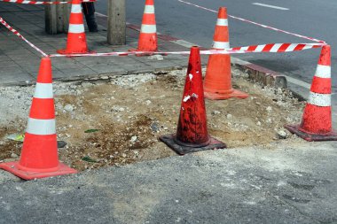 İnşaat alanındaki bir caddenin yanında bir sürü trafik konisi var..
