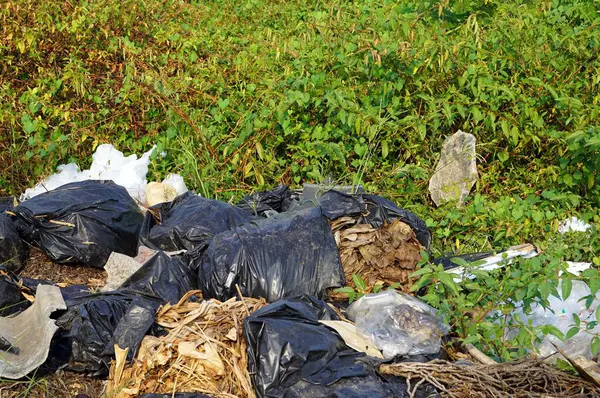 A pile of many plastic garbage on the ground backside ia a grass, environmental pollution concepts.