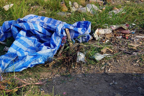 A pile of many garbage on the ground backside is a grass, environmental pollution concepts.