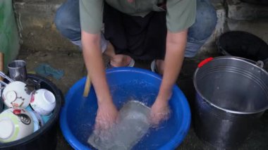 Çalışanlardan biri mavi plastik kaptaki alüminyum kutuyu temizliyormuş. Elle su içiyormuş..