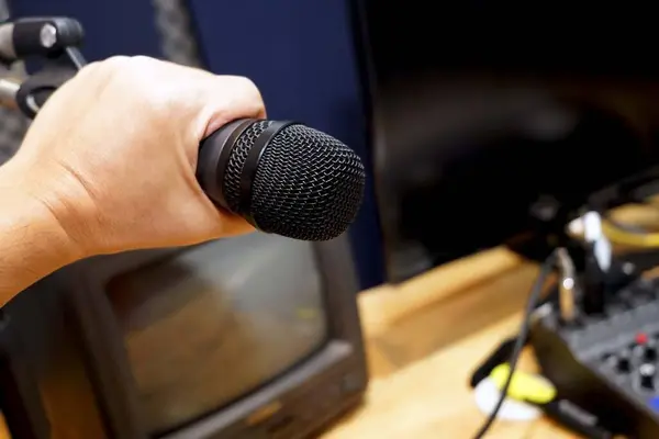 Close up of Microphone in the hands of a producer to control sound dubbing in the reccordding room.
