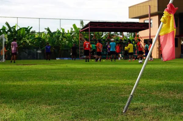 stock image Close up a flagpole of the football field back side of a group of people are playing soccer in a field.