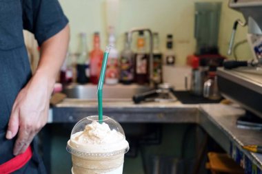 Barista, kahvecide bir müşteriye teslim edilecek yumuşak bir kahve hazırlıyor..