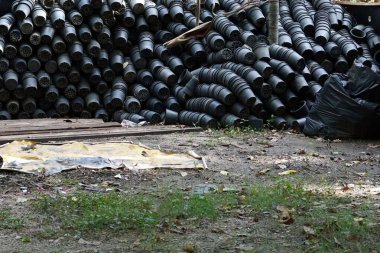 Parkta bir sürü eski siyah plastik saksı yığını var.. 