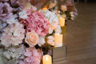 Salon çiçeklerin içinde boğulmuştu: gül ve şakayık çiçekleri, masaların üzerinde okaliptüs olan zarif buketler ve yol boyunca bir yaprak serpintisi, mumların yanıp sönmesiyle aydınlandı..