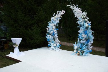 Salon çiçeklerin içinde boğulmuştu: gül ve şakayık çiçekleri, masaların üzerinde okaliptüs olan zarif buketler ve yol boyunca bir yaprak serpintisi, mumların yanıp sönmesiyle aydınlandı..