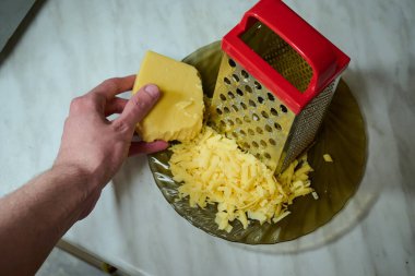 Mutfaktaki bir kase üzerinde ızgara peynirin işlem süreci..