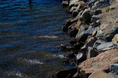 Temiz göl suyu, kayalık zemine güneşi yansıtır..